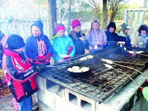 Students from Ste. Marguerite Bourgeoys, Pope John Paul II and St. Louis schools baked bannock the traditional way — on a stick over a fire — during a visit to the Wauzhushk Onigum Fall Harvest at Powwow Island on Monday