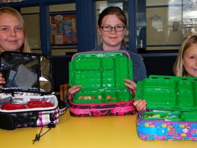 John Wise Public School Grade 7 students Faith Elsdon, left, and Madison Thompson, along with Grade 2 student Avery De Vree, showcase their waste-free lunches in the school library on Tuesday. The school is one of many taking part in the Waste-Free Lunch Challenge, in which students pledge to bring a waste-free lunch every day this week. Prizes will be given to 21 classrooms or schools in Ontario that reduce the largest amount of waste.