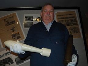 Elgin Military Museum executive director Ian Raven holds a white practice bomb from the Second World War and an empty shell casing from an anti-tank round at the museum on Wednesday, Oct. 23, 2013. The ammunition is not live and was donated to the museum after a 94-year-old woman brought it to the police station Tuesday, police said. Ben Forrest/QMI Agency/Times-Journal