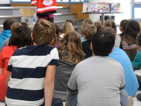 Author Lorna Nicholson illustrates one of her stories using a hockey jersey, at her presentation at St. Jerome's School on Friday, Oct. 18.