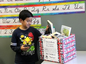 10-year-old Julian Rincon donates a book to The Organization for Literacy's annual Give-A-Book campaign. MELANIE ANDERSON/THE OBSERVER/QMI AGENCY