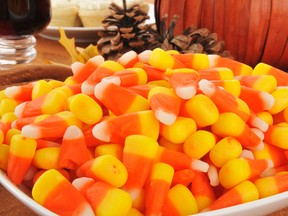 Close up of a bowl of candy corn on a table with a pumpkin centerpiece. (Fotolia.com)
