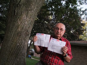 Sarnia homeowner Louis Joe shows off repair bills after he says a city tree's roots damaged the drainage system at his Laurier Crescent home. He has now been saddled with more than $11,900 in expenses after he says the city's adjuster denied his insurance claim. BARBARA SIMPSON / THE OBSERVER / QMI AGENCY