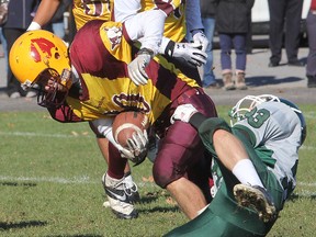 Regiopolis-Notre Dame’s Sean Mombourquette tries to shake off a tackle by Holy Cross’ Grant Chenier during Kingston Area Secondary Schools Athletic Association senior AAA football semifinal action at Holy Cross Tuesday afternoon. The Crusaders won 17-11 in overtime. (Michael Lea/The Whig-Standard)
