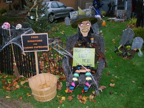 A witch guards a basket for donations to the Caring Cupboard Food Bank on David Dr. in St. Thomas. This is one of several homes on the street that go all out with Halloween decorations each year.