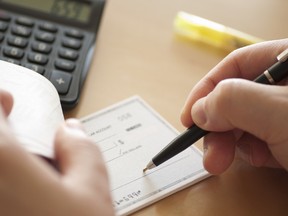 Man writes a check. (Fotolia.com)