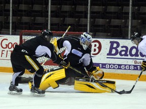 Sarnia Sting goaltender Taylor Dupuis stretches to make a save on forward Davis Brown (in white) while Craig Duininck defends at  practice on Thursday, Oct. 31. The Sting had a long week of practice to get ready for the Soo Greyhounds on Friday night. SHAUN BISSON/THE OBSERVER/QMI AGENCY