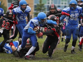 Griffin Brown and Nathan Dhanoa help Cumberland Panthers RB Fahan Younus run the ball against Myers Riders in Peewee action.
