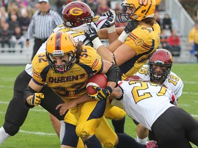 Queen's Ryan Granberg gets through traffic past Guelph's Jadon Johnson to gain yardage during Saturday afternoon's game at Richardson Stadium on Oct. 19. (Michael Lea/The Whig-Standard)