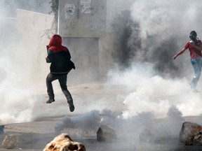 Palestinian protesters are seen amidst tear gas smoke fire by Israeli troops during clashes following a protest against the expropriation of Palestinian land by Israel in the village of Kfar Qaddum, in the northern West Bank, on November 1, 2013.  AFP PHOTO/JAAFAR ASHTIYEH