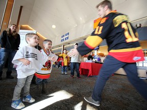 Brothers Caleb (left) and Cole White of Belleville, Ont. share a high five with Belleville Bulls' left winger Michael Cramarossa during the 5th Annual Breakfast with the Belleville Bulls in Belleville, Ont. last year. - FILE PHOTO BY JEROME LESSARD/The Intelligencer