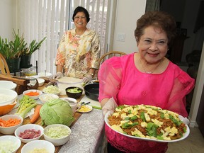 Tessie Torres, foreground, and Marieta Kenyon show some of the dishes they have been preparing. (Michael Lea The Whig-Standard)