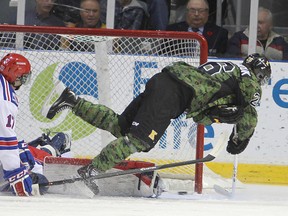 Frontenacs' Sam Povorozniouk goes airborne as he scores on Kitchener goalie Jordan DeKort  as Rangers' Mason Kohn looks on during first period action in Friday night's game at the Rogers K-Rock Centre. (Micheal Lea/The Whig-Standard)