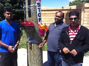 Relatives of Manoranjana Kanagasabapathy, Yathu Yogi, left, his dad Yogi Thambi, centre and Thambi's brother-in-law Vijay Nadarajah drop flowers on Aug. 14 at the Scarborough corner where the 52-year-old woman was killed as she boarded a TTC bus. (CHRIS DOUCETTE/Toronto Sun)