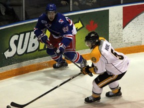 Sarnia Sting defenceman Tyler Hore strips the puck from Kitchener Rangers forward Mike Davies during the second period of their game in Sarnia on Thursday, Nov. 14, 2013. Hore opened the scoring for Sarnia early in the first period with a slapshot that would wind up being the game winner in a 5-0 Sting victory. (SHAUN BISSON, The Observer)