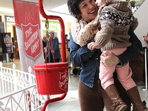 Two-year-old Nescia Giangrosso, held by her mother Janza, prepares to reach down to put a coin in the Salvation Army Christmas kettle at the Cataraqui Centre Friday afternoon as the annual kettle campaign kicked off.
Michael Lea The Whig-Standard