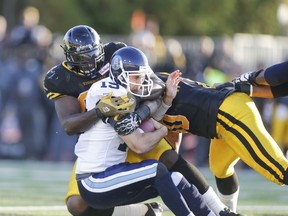 Toronto Argonauts quarterback Ricky Ray gets tackled by  Hamilton Tiger-Cats Torrey Davis (left) and Eric Norwood earlier this year. (Ernest Doroszuk, Toronto Sun)