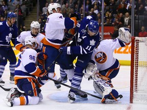 Maple Leafs centre Jay McClement gets tangled up with Matt Carkner in front of Islanders goaltender Kevin Poulin on Tuesday night. (DAVE ABEL/Toronto Sun)