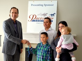 Pacesetter Homes representative Zan Owsley gives the Sanchez family the key to their new home on behalf of Habitat Edmonton. - April Hudson, Reporter/Examiner