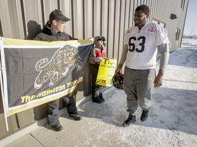 Moose Jaw resident and Hamilton Tiger-Cats fan Derek Thomas, and his son David, greet Marc Dile and the Tabbies following a morning practice yesterday. At left, a frozen football is left to die on the Mosaic Stadium turf yesterday during the Roughriders’ final workout. (Lyle Aspinall/QMI Agency)