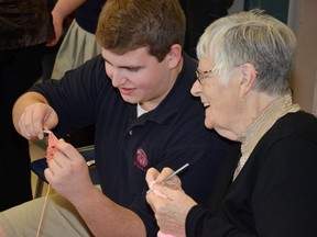 Grade 12 student Nick Rawlings gets the hang of how to crochet, with a little help from volunteer grandma Alice Hakkers.