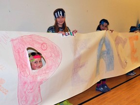 St. Columban students Hannah Nolan (left), Kimmi Doyle and Jenna Deck hold a portion of their Peace, Really banner the students’ council displayed for their colleagues during an anti-bullying assembly at the school Wednesday, Nov. 27. ANDY BADER/MITCHELL ADVOCATE