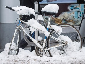 A man walks in downtown Ottawa past a snow-covered bicycle after the city received its first substantial snowfall of the season. Nov. 27,2013. Errol McGihon/Ottawa Sun/QMI Agency
