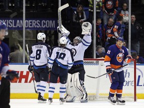 Nov 27, 2013; Uniondale, NY, USA; Winnipeg Jets goalie Al Montoya (35) celebrates with defenseman Jacob Trouba (8) and center Bryan Little (18) in front of New York Islanders right wing Kyle Okposo (21) following a game at Nassau Veterans Memorial Coliseum. The Jets defeated the Islanders 3-2. Mandatory Credit: Brad Penner-USA TODAY Sports