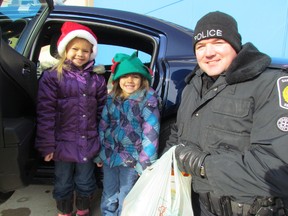 Sisters, from left, Alyson Laird, 6, and Katelyn Laird, 4, drop off a donation with Const. Jim McCabe at a Cops for Cans event Saturday at the Walmart parking lot in Sarnia. Members of the Sarnia Police, along with student volunteers, were gathering food donations for the Inn of the Good Shepherd food bank. PAUL MORDEN/ THE OBSERVER / QMI AGENCY