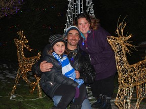 Kiara Szabo, left, of London, threw a switch that lit over 65,000 Christmas lights at a home in Port Stanley on Saturday. Szabo has leukemia and is headed to Hawaii after Christmas thanks to the Make-a-Wish Foundation of Southwestern Ontario. The Christmas display in Port Stanley is collecting donations for Make-a-Wish. Szabo is pictured with her father John and mother Roxanne. (Ben Forrest, Times-Journal)
