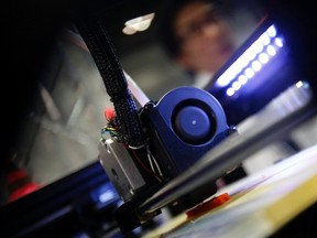 A staff member of Nihonbinary looks at its 3D printer MakerBot Replicator 2 as it prints a Polylactic acid fish shape accessory during the International Robot Exhibition 2013 in Tokyo Nov. 8, 2013. REUTERS/Yuya Shino