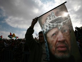 A Palestinian holds a banner depicting the late Palestinian leader Yasser Arafat during a rally in the West Bank city of Ramallah marking the third anniversary of his death in this November 11, 2007 file photo.REUTERS/Oleg Popov/Files
