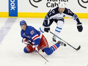 New York Rangers left wing Benoit Pouliot (67) keeps the puck from Winnipeg Jets defenseman Mark Stuart (5) during the third period at Madison Square Garden. Winnipeg Jets won 5-2. 
Anthony Gruppuso-USA TODAY Sports