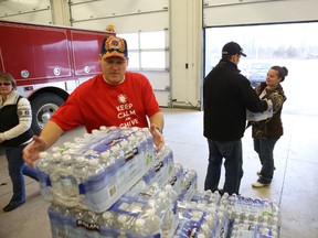 Loyalist firefighters hand out cases of bottled water to residents after a drinking water advisory was put in place for most of the township. The advisory is expected to remain in place until near the end of the week.
Elliot Ferguson The Whig-Standard