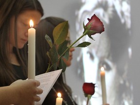 Roses and candles, to remember the 14 women killed at Ecole Polytechnique in Montreal on Dec. 6, 1989, are held by Queen's University students during a ceremony on campus Friday afternoon as photos of the victims are projected on a screen.
Michael Lea The Whig-Standard