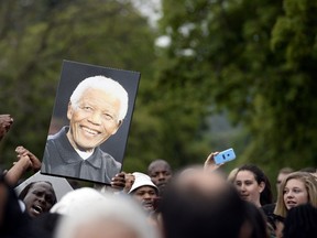 Mourners holding a picture of late former South African president Nelson Mandela sing outside his house in Johannesburg on December 6, 2013. (AFP PHOTO / STEPHANE DE SAKUTIN)
