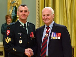 Canadian Armed Forces Sgt. Caleb W. McPhail, left, receives a Medal of Bravery from Governor General David Johnston Thursday at Rideau Hall in Ottawa. McPhail, who lives in St. Thomas, was recognized for helping evacuate the residents of a burning apartment building in 2010.