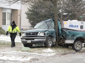 A member of the London Police traffic reconstruction division walks past a stolen pickup truck that struck a tree on Admiral Drive near Bonaventure Drive about 2:15 a.m. in London, Ont. on Wednesday December 11, 2013.  The male driver of the pickup was taken to hospital where he died from his injuries. (CRAIG GLOVER, The London Free Press)