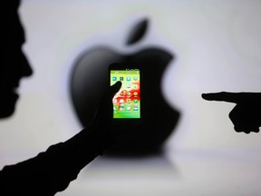 Men are silhouetted against a video screen with an Apple Inc logo as they pose with a Samsung Galaxy S3 smartphone in this photo illustration taken in the central Bosnian town of Zenica, May 17, 2013.  REUTERS/Dado Ruvic