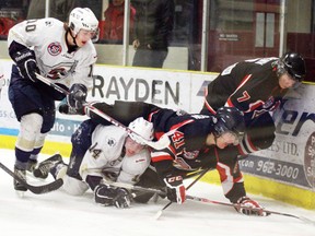 Saints rookies Tyler Busch (10) and Austin Hunter (14) team up against two Camrose players in a battle for the puck along the wall during their game in the Grove. The pair have been a big part in the Saints success this year, as the team moved into the top  spot in both the AJHL and the CJHL national standings with a 4-3 win in this game along with a 6-1 win in Bonnyville. - Gord Montgomery, Reporter/Examiner