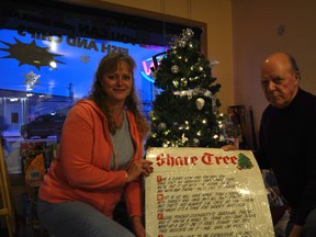 Kim Currie (left) and Ken Scott pose in front of the Share Tree at Docherty’s in Spruce Grove. - Thomas Miller, Reporter/Examiner