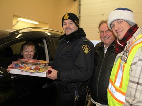 Jennifer Deslippe, of Corunna, hands toys to OPP Const. Paul Primeau, left, Operation Christmas Tree chairman Fred Strickland, and Shaun Antle, chairman of the Corunna Community Policing Committee, during the annual goods drive-through on Saturday. In total, the event collected more than 1,450 food items and toys, along with more than $1,000 in cash.