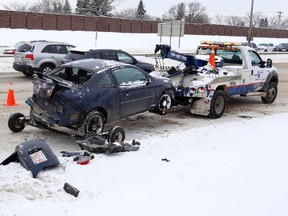 A tow truck operator works on clearing the the debris from a two vehicle crash that occurred after 11 am on Saturday,. Things got a lot worse when freezing rain moved in later. (TOM BRAID/Edmonton Sun)