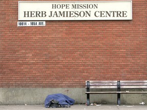 A homeless person lays on the sidewalk outside the Herb Jamieson Centre, 10014 - 105 Ave.