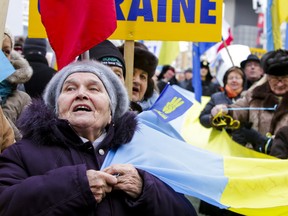Maria Kowal — holding a giant Ukrainian flag — was one of many demonstrators who turned out to Yonge-Dundas Square on Sunday. (ERNEST DOROSZUK, Toronto Sun)