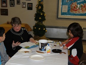 Archdeacon Deborah Lonergan-Freake (middle) reading Dylan Dubeault and Aaron Lavoie the story of Moses while they complete a Moses themed craft during Messy Church on Nov. 26.