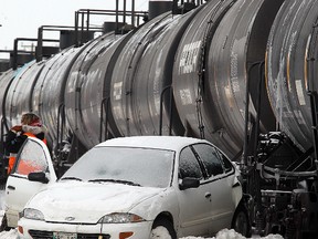A rail worker examines a car that was in collision with a train on the CPR Emerson track on Bishop Grandin near Lakewood in Winnipeg, Man. Monday, Dec. 16, 2013. There were no injuries reported in the collision. (Brian Donogh/Winnipeg Sun)
