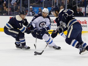 Winnipeg Jets left wing Eric Tangradi (27) skates with the puck between Columbus Blue Jackets defensemen Jack Johnson (7) and David Savard (58) during the first period at Nationwide Arena. (Russell LaBounty-USA TODAY Sports)