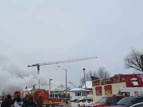 The rescue helicopter emerges from the smoke before plucking a trapped crane operator at the end of the boom, as a fire torched a building under construction in Kingston Tuesday.