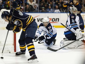Buffalo Sabres right wing Brian Flynn (65) tries to control a loose puck behind Winnipeg Jets goalie Ondrej Pavelec (31) as defenseman Tobias Enstrom (39) defends during the second period at First Niagara Center. Mandatory Credit: Kevin Hoffman-USA TODAY Sports